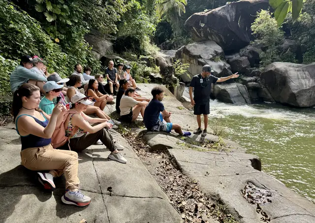 Local guide briefing a large guest group on the rocks beside Charco El Hippie river