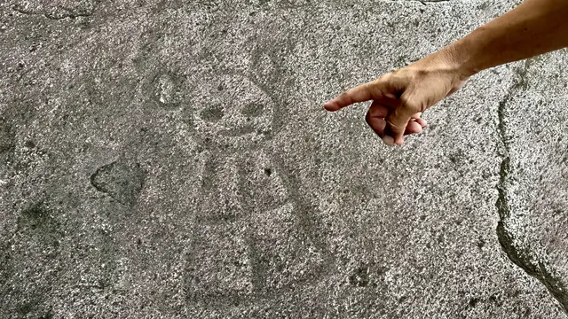 Guide pointing out ancient Taino petroglyphs carved into the river rocks at Charco El Hippie