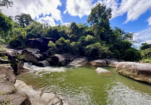 Wide natural swimming pool at Charco El Hippie surrounded by jungle and blue sky Naguabo Puerto Rico