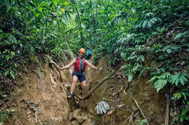 Guests climbing volcanic rocks beside waterfall