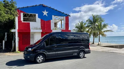 Paradise Seekers Puerto Rico tour van parked oceanside next to a building painted with the Puerto Rican flag