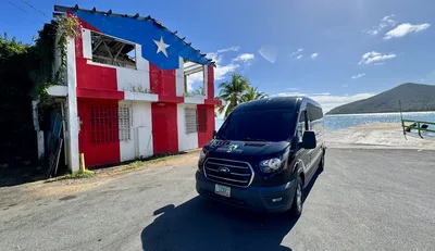 Paradise Seekers Puerto Rico transportation van parked oceanside next to a Puerto Rican flag building